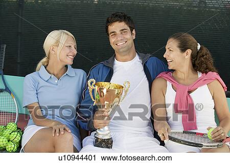 Tennis players sitting at tennis court, man holding trophy, front view, portrait View Large Photo Image Stock Image - Tennis players sitting at tennis court, man holding trophy, front view, portrait. Fotosearch