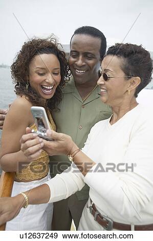 Three Friends Using Cell Phone on Yacht View Large Photo Image Stock Photo - Three Friends Using Cell Phone on Yacht. Fotosearch