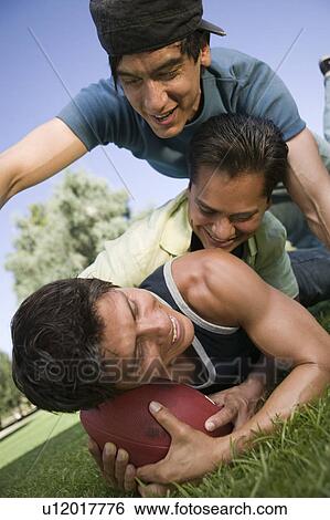 Three young men playing football. View Large Photo Image Stock Photograph - Three young men playing football.. Fotosearch