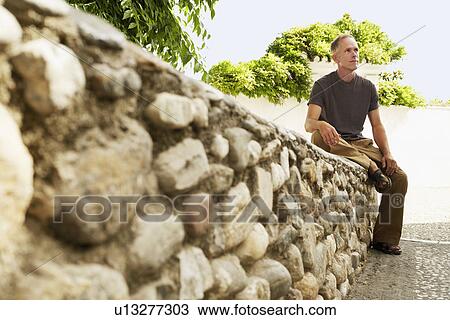 Stock Image - Tourist sitting on Stone Wall in Granada, Spain. Fotosearch