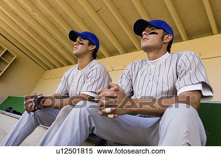 Two baseball team-mates sitting in dugout, (low angle view) View Large Photo Image Stock Photography - Two baseball team-mates sitting in dugout, (low angle view). Fotosearch