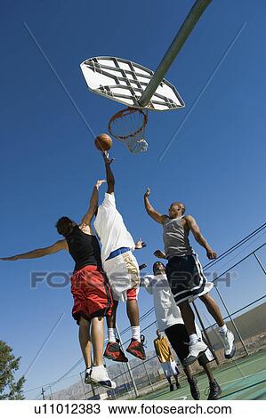 Two basketball players guarding another as he tries to shoot basketball, low angle view View Large Photo Image Stock Image - Two basketball players guarding another as he tries to shoot basketball, low angle view. Fotosearch
