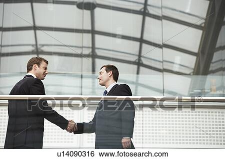 Stock Photograph - Two Businessmen Shaking Hands, side view. Fotosearch
