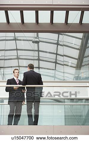 Stock Image - Two Businessmen Talking in office. Fotosearch