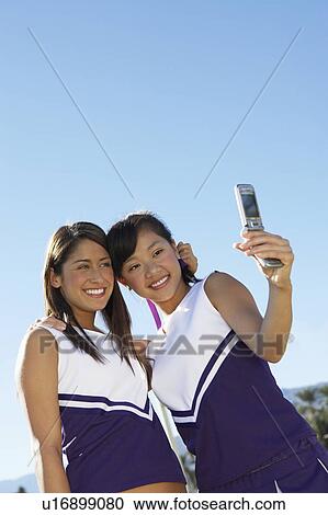 Two Cheerleaders Taking Photo of Themselves with Camera Phone, low angle view View Large Photo Image Stock Image - Two Cheerleaders Taking Photo of Themselves with Camera Phone, low angle view. Fotosearch