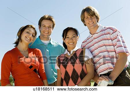 Stock Image - Two couples posing on golf course, (portrait). Fotosearch