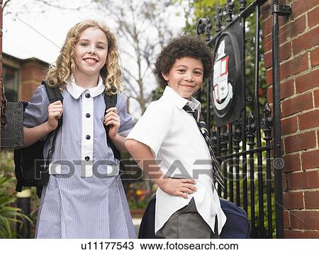 Stock Image - Two elementary students standing at school gate, portrait. Fotosearch