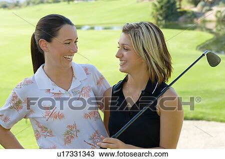 Stock Image - Two female golfers laughing to each other. Fotosearch