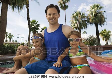 Two girls (7-9) sitting with father by pool, portrait. View Large Photo Image Picture - Two girls (7-9) sitting with father by pool, portrait.. Fotosearch