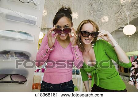 Two Girls Trying on Sunglasses in Boutique, portrait View Large Photo Image Stock Image - Two Girls Trying on Sunglasses in Boutique, portrait. Fotosearch