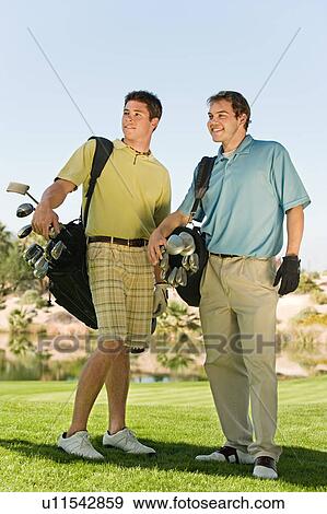 Two golfers standing next to each other on golf course View Large Photo Image Stock Photo - Two golfers standing next to each other on golf course. Fotosearch
