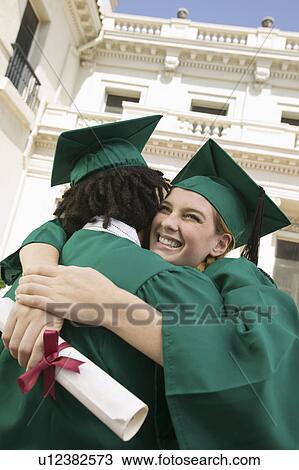 Stock Image - Two graduates hugging outside university. Fotosearch