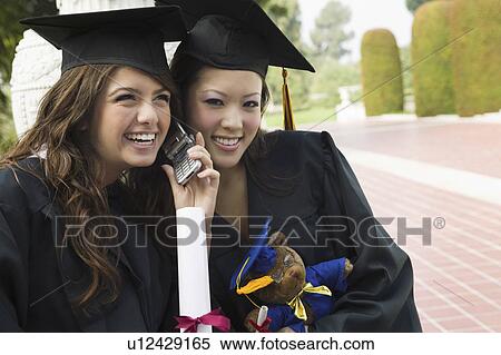 Two graduates using cell phone outside View Large Photo Image Stock Photography - Two graduates using cell phone outside. Fotosearch