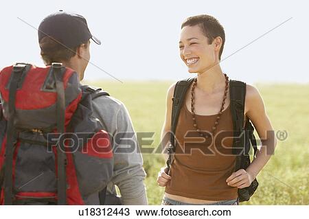 Stock Image - Two hikers talking, standing in field. Fotosearch