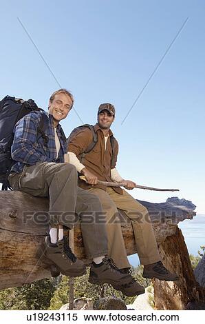 Stock Photography - Two male hikers sitting on log, (portrait). Fotosearch