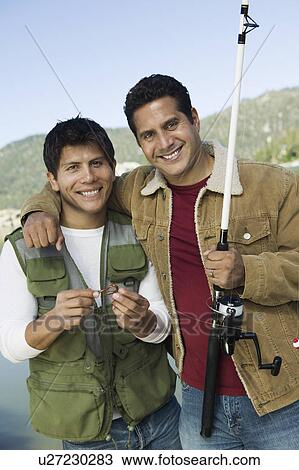 Stock Image - Two men fly fishing on lake, (portrait). Fotosearch