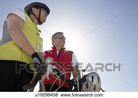 Stock Photo - Two men on bicycle ride, portrait, low angle view. Fotosearch