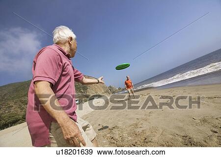 Two men playing with flying disc on beach View Large Photo Image Stock Photo - Two men playing with flying disc on beach. Fotosearch