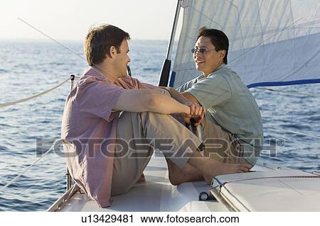 Two men relaxing on sailboat View Large Photo Image Stock Image - Two men relaxing on sailboat. Fotosearch