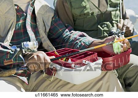 Two men using tackle box and preparing fishing pole, (close-up), (mid section) View Large Photo Image Stock Photography - Two men using tackle box and preparing fishing pole, (close-up), (mid section). Fotosearch
