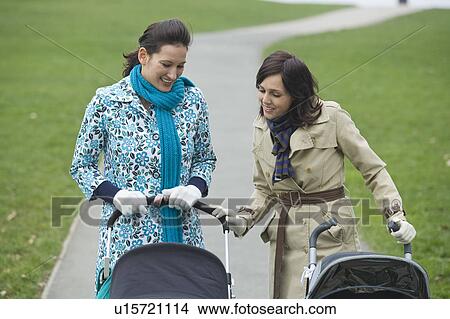 Picture - Two mothers in park looking at their babies in strollers. Fotosearch