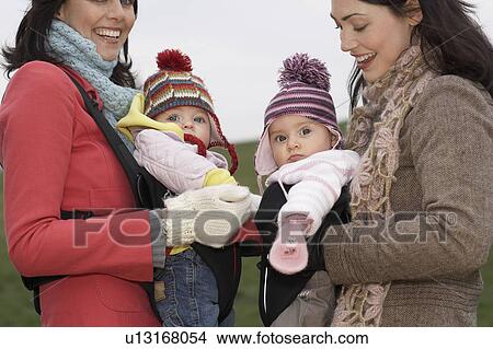 Two mothers in park with babies in slings standing face to face, (mid section) View Large Photo Image Picture - Two mothers in park with babies in slings standing face to face, (mid section). Fotosearch