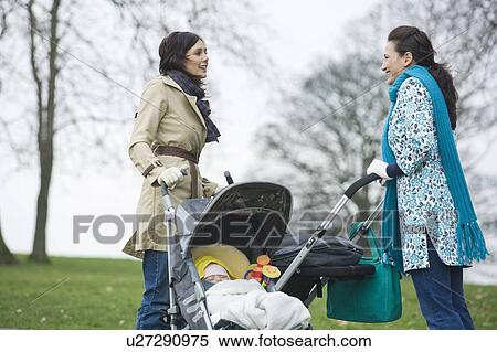 Stock Photography - Two mothers in park with babies in strollers. Fotosearch