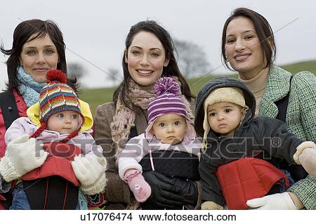 Two mothers with babies in baby carriers in park View Large Photo Image Picture - Two mothers with babies in baby carriers in park. Fotosearch
