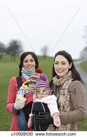 Two mothers with babies in baby carriers in park View Large Photo Image Stock Image - Two mothers with babies in baby carriers in park. Fotosearch