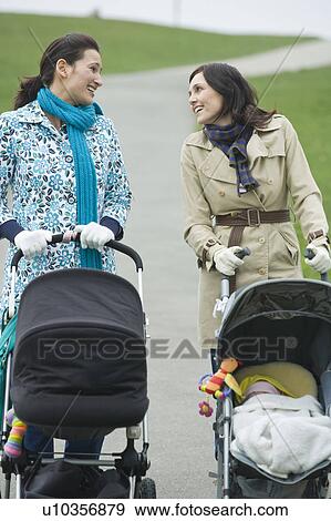 Two mothers with strollers in park having chat View Large Photo Image Stock Photo - Two mothers with strollers in park having chat. Fotosearch