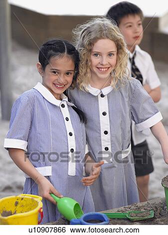Stock Photograph - Two school girls playing in playground, portrait. Fotosearch
