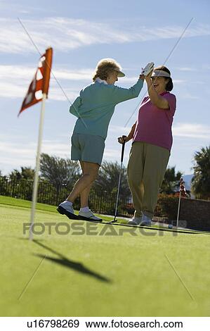 Stock Photo - Two women giving high-five on golf course. Fotosearch