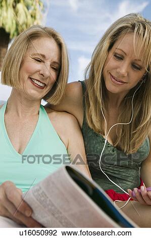 Two women reading magazine outdoors. View Large Photo Image Stock Image - Two women reading magazine outdoors.. Fotosearch