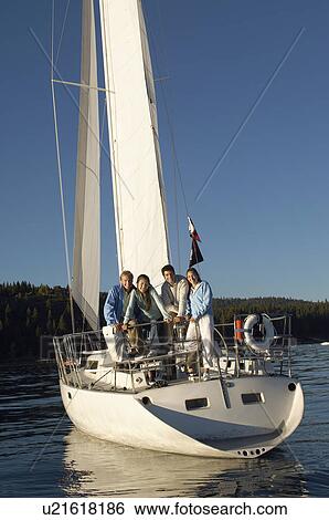 Stock Photograph - Two young couples standing on stern of sailboat. Fotosearch