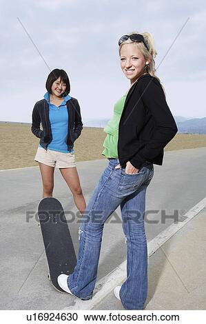 Stock Image - Two young female skateboarders on road. Fotosearch