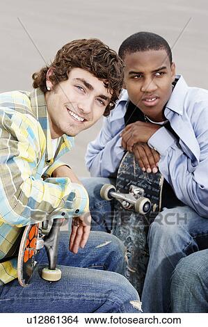 Two young skateboarders sitting outside View Large Photo Image Picture - Two young skateboarders sitting outside. Fotosearch