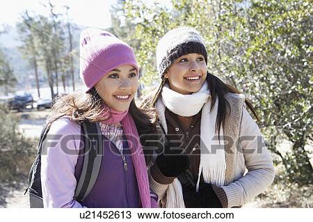 Two young women in warm clothes, standing outdoors, smiling. View Large Photo Image Stock Image - Two young women in warm clothes, standing outdoors, smiling.. Fotosearch
