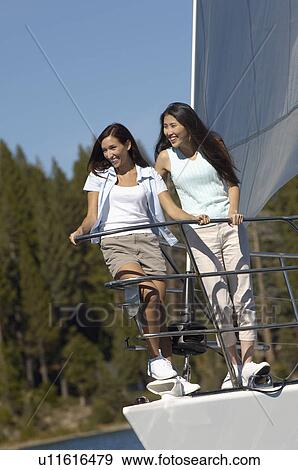 Stock Photo - Two young women standing on bow of sailboat. Fotosearch