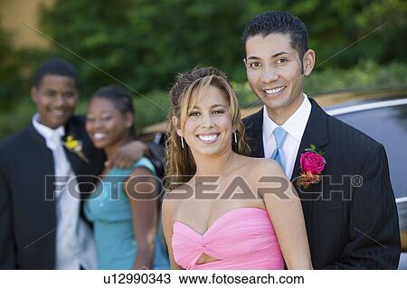 Stock Image - Well-dressed teenage couple outside car, portrait. Fotosearch