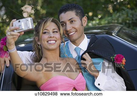Stock Photo - Well-dressed teenage couple taking picture outside car. Fotosearch