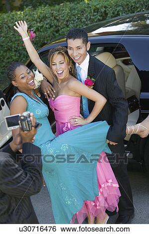 Stock Photograph - Well-dressed teenage couples posing an video taping selves outside. Fotosearch