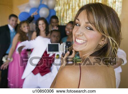 Well-dressed teenager girl video taping friends at school dance View Large Photo Image Stock Photograph - Well-dressed teenager girl video taping friends at school dance. Fotosearch