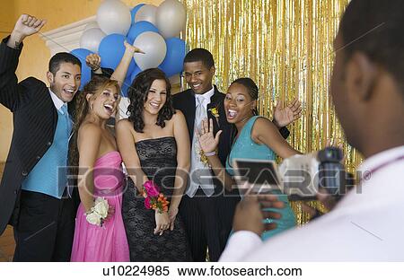Stock Photography - Well-dressed teenagers posing for video camera at school dance. Fotosearch