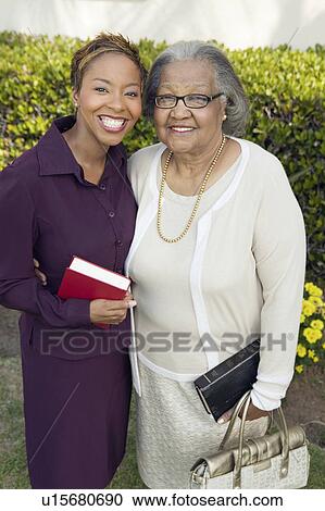 Stock Image - Woman and Mother standing in garden with Bibles, portrait. Fotosearch