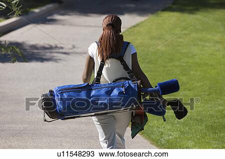 Woman carrying golf club bag, rear view View Large Photo Image Stock Image - Woman carrying golf club bag, rear view. Fotosearch