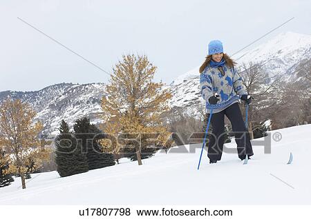Stock Photo - Woman cross-country skiing in snow covered field. Fotosearch