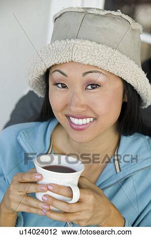 Stock Image - Woman drinking coffee, smiling, (portrait). Fotosearch