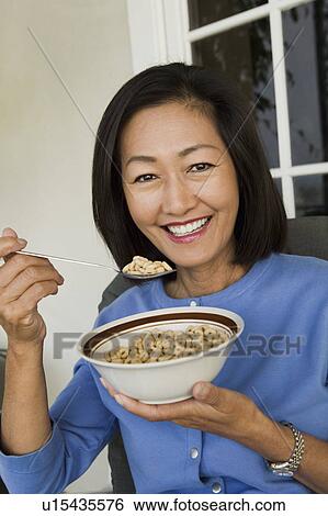 Woman eating breakfast cereal outdoors, (portrait) View Large Photo Image Stock Photograph - Woman eating breakfast cereal outdoors, (portrait). Fotosearch