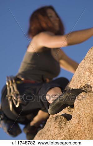 Stock Image - Woman Free Climbing, (close-up), (low angle view). Fotosearch