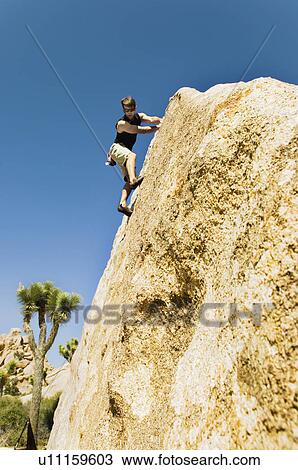 Stock Image - Woman Free Climbing on Cliff, side view. Fotosearch